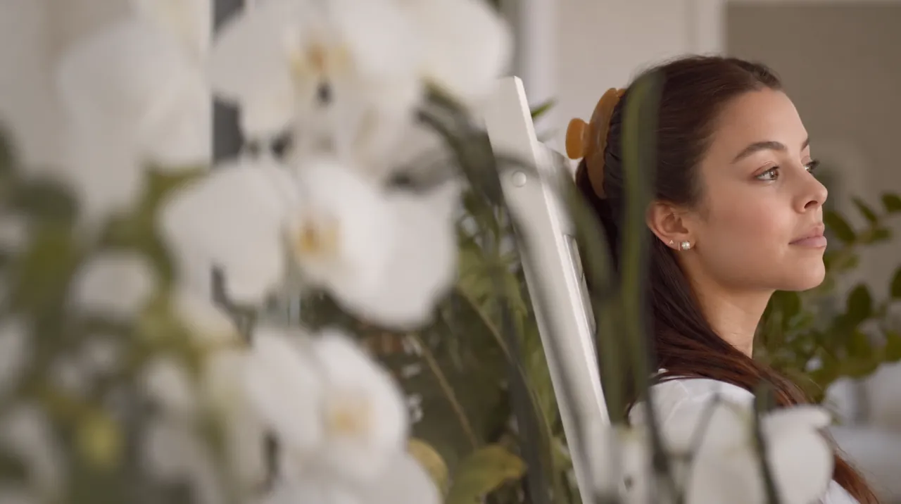 Ana in a reflective profile through softly blurred flowers
