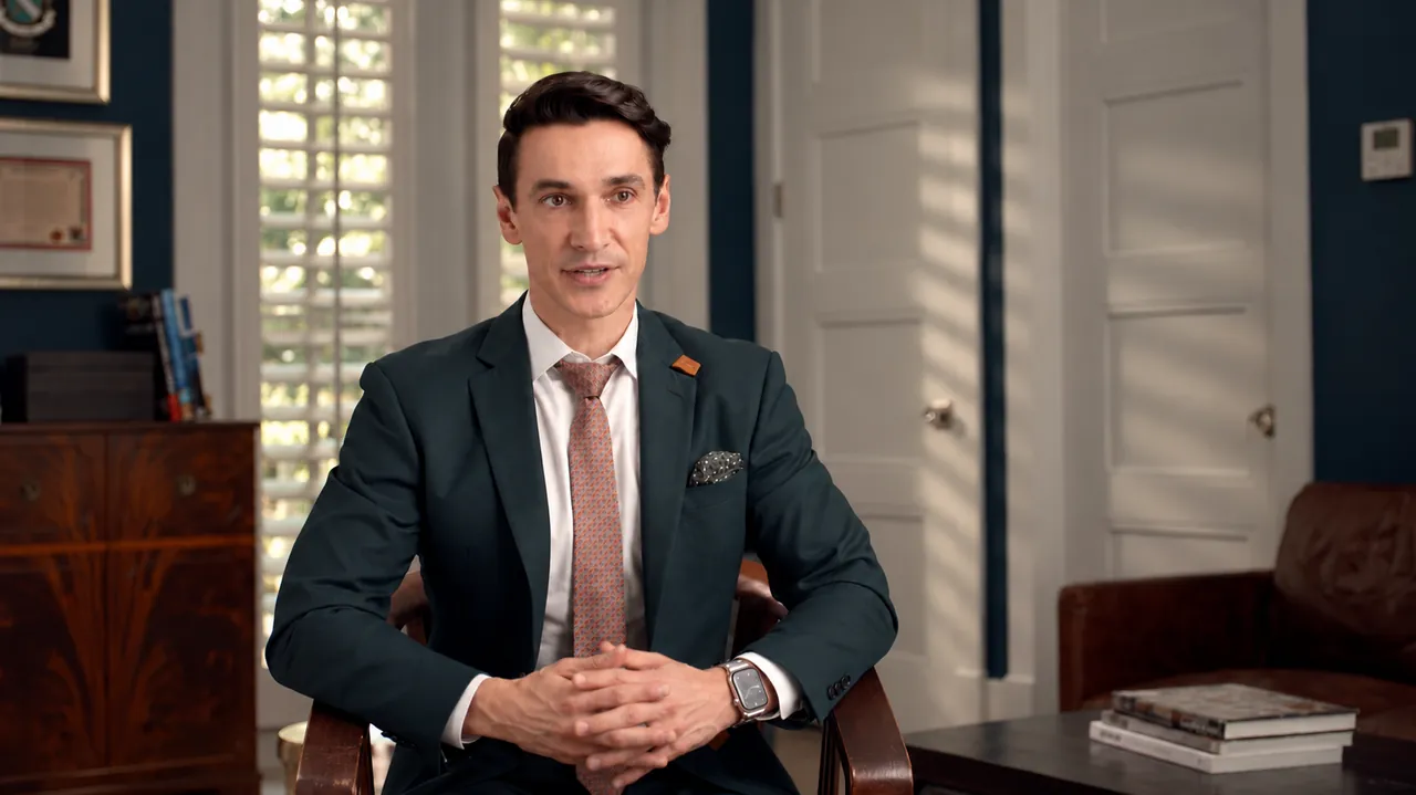 The doctor seated for his interview in a dark teal suit